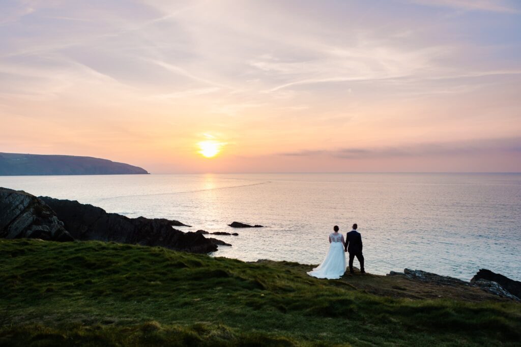 wedding couple at the cliff hotel and spa, wedding couple looking out to the sea with the sun setting,