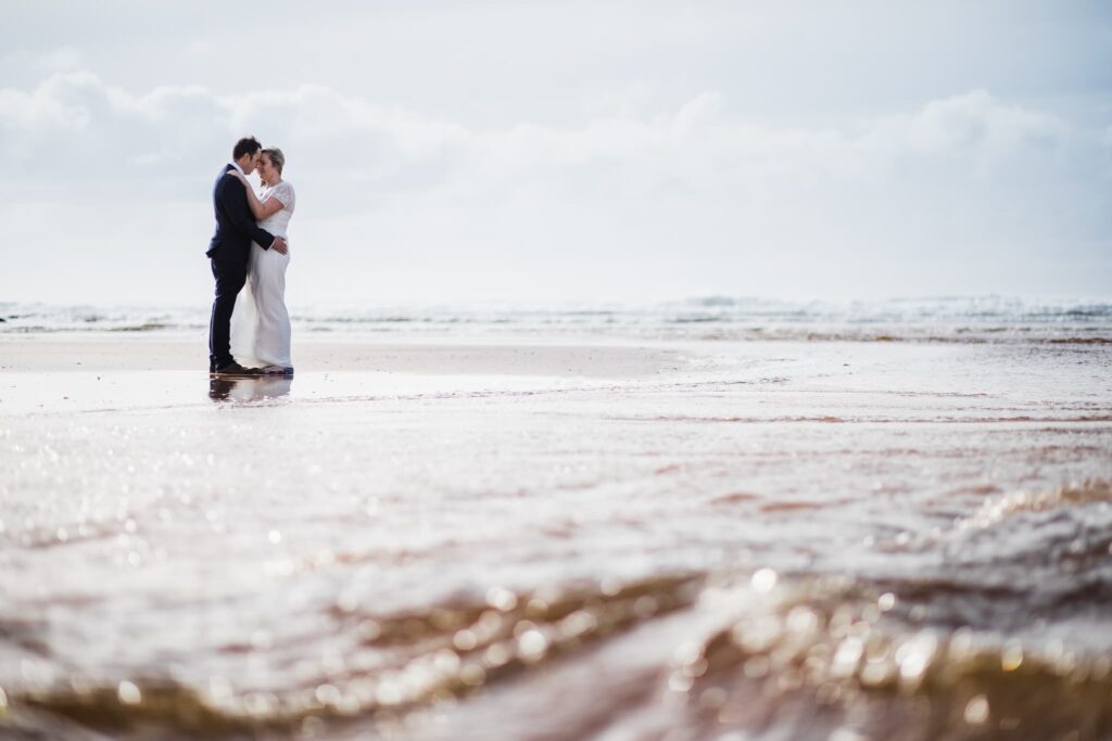 freshwater west beach, elopement photo, couple hugging, river water in the foreground, west wales elopement, 