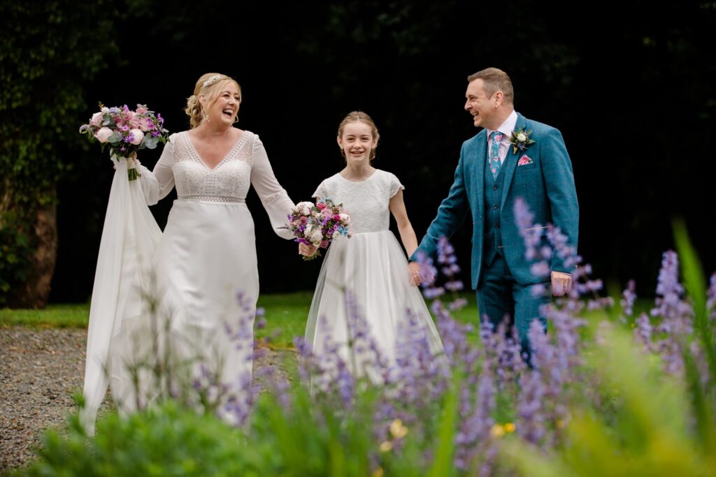Wedding couple and child walking, purple flowers in wedding photos. west wales elopement, 