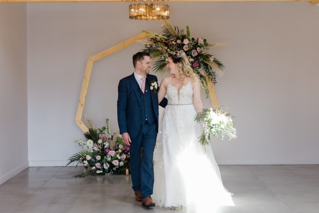 wedding couple by their flowered archway, ceremony room, 