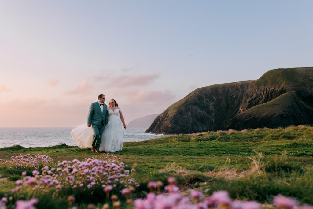 pembrokeshire wedding elopement, ceibwr costal path, flowers in forground wedding, couple walking, ceibwr cliffs