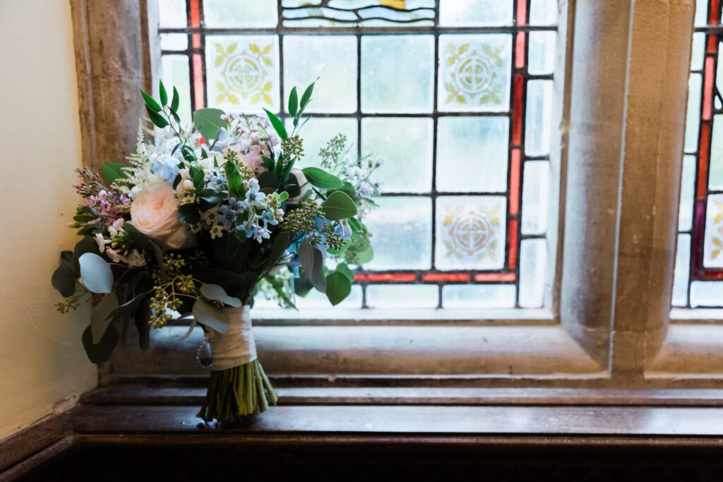 wedding bouquet leant against stained glass window, 